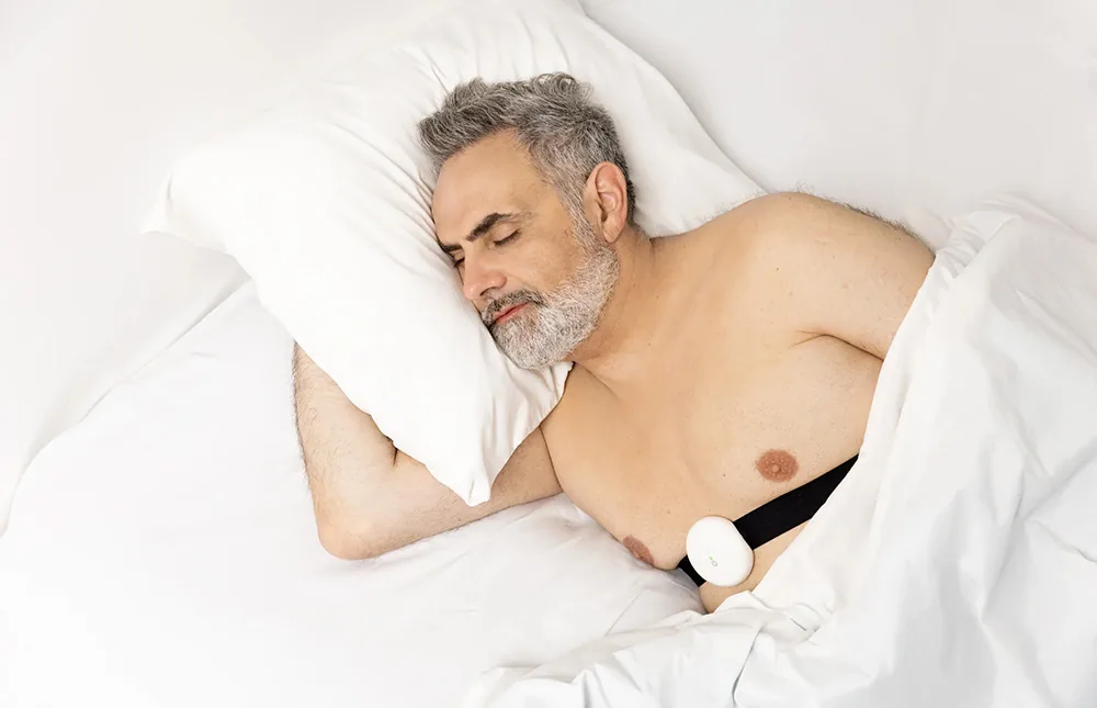 A woman sleeps at home with Aidmed One and a fingertip pulse oximeter